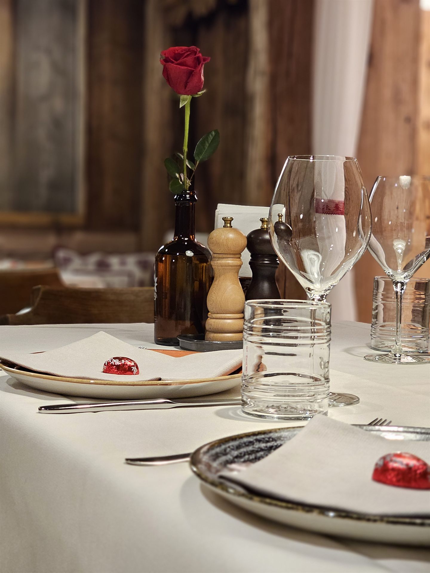 Gedeckter Tisch in der Stube mit roter Rose und Willkommenspraline