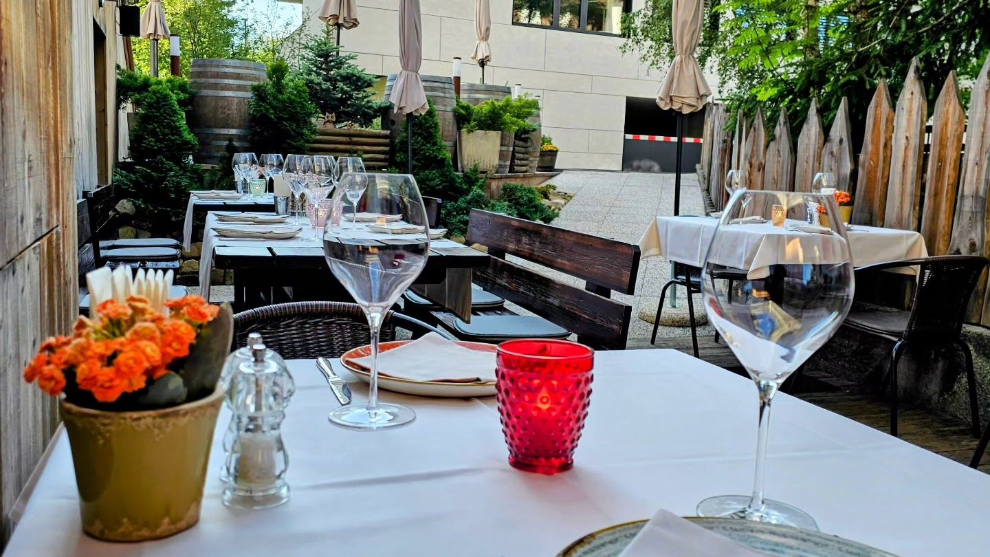 Die Gartenterrasse mit Tischen, Weinfässern und Sonnenschirmen