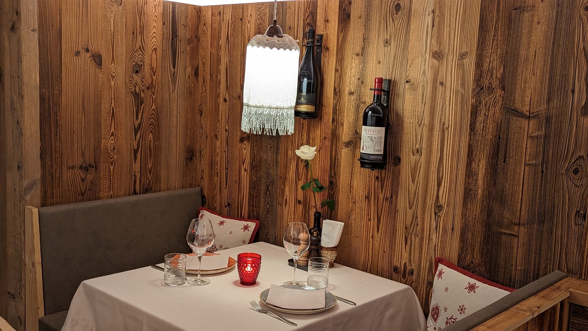 Ecktisch in der Holzstube mit Weinflaschen an der Wand