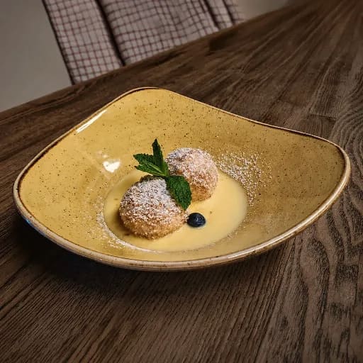 Süße Krapfen mit Puderzucker auf Vanillesauce