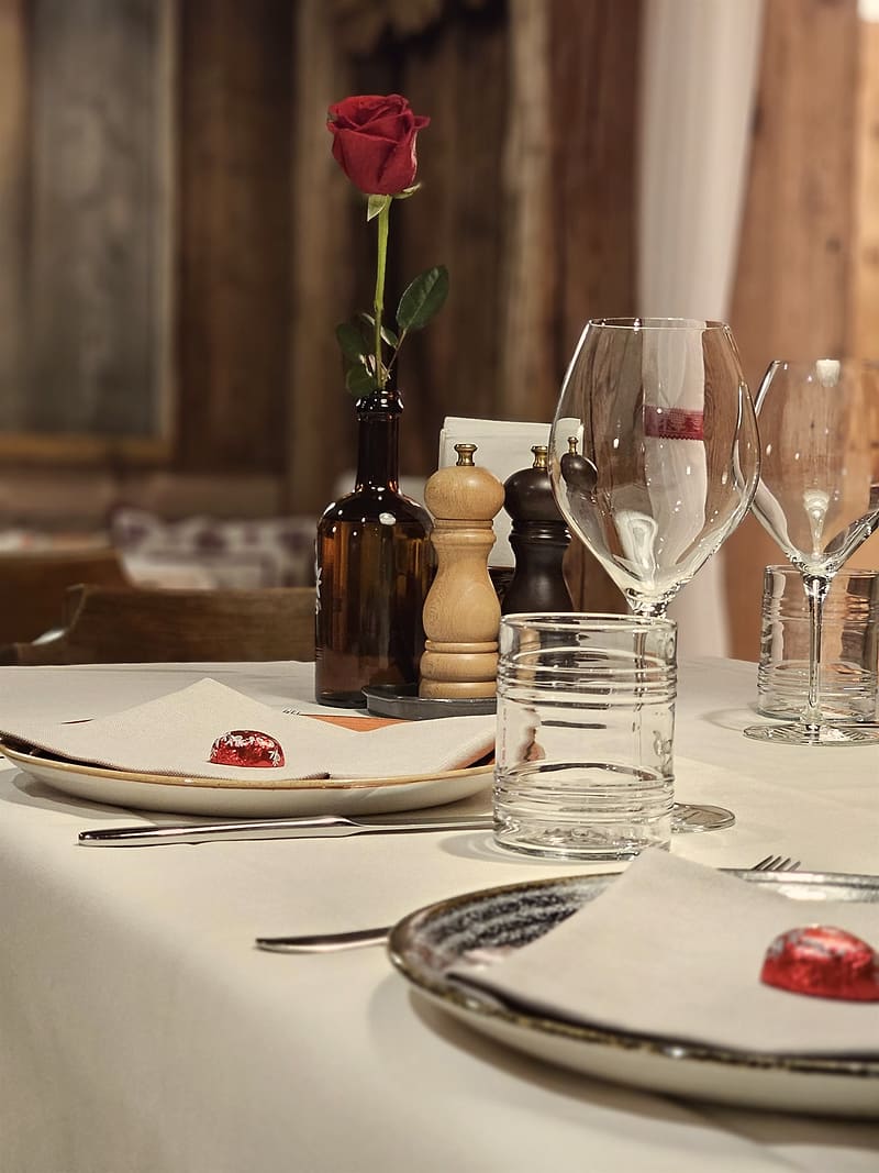 Gedeckter Tisch in der Stube mit roter Rose und Willkommenspraline