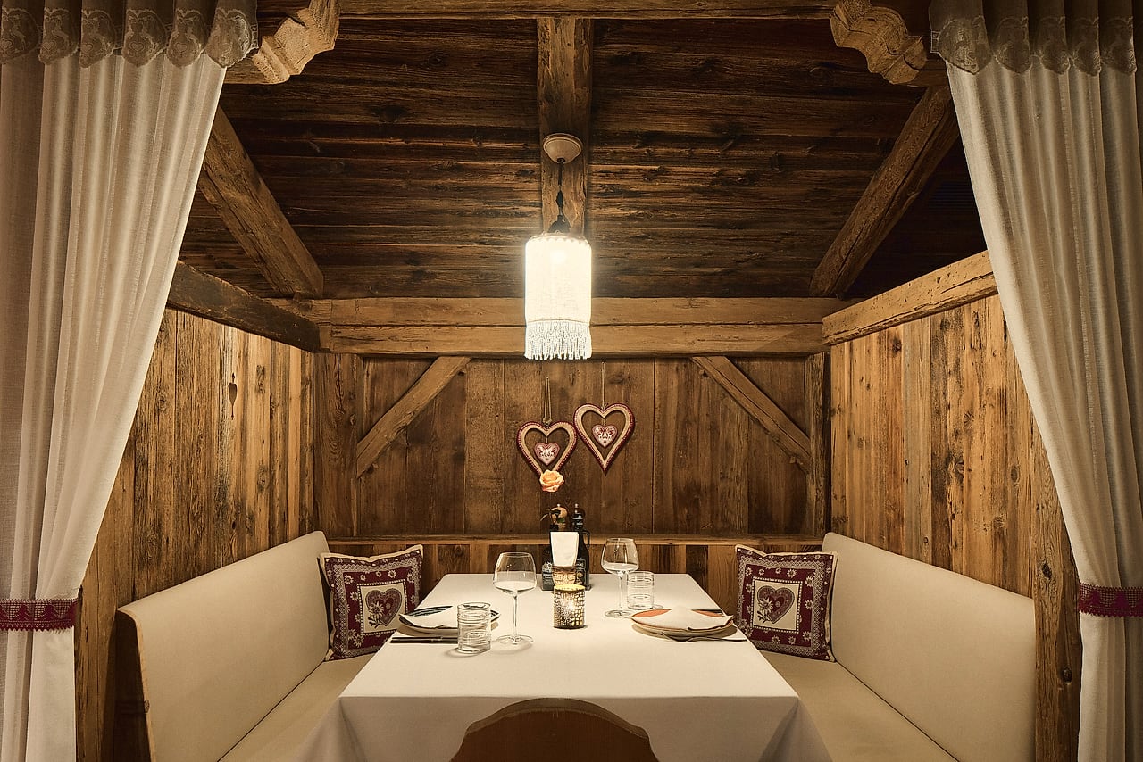 Die Stube im Adlerkeller: Nische aus altem Holz mit Tiroler Herzen und gedecktem Tisch