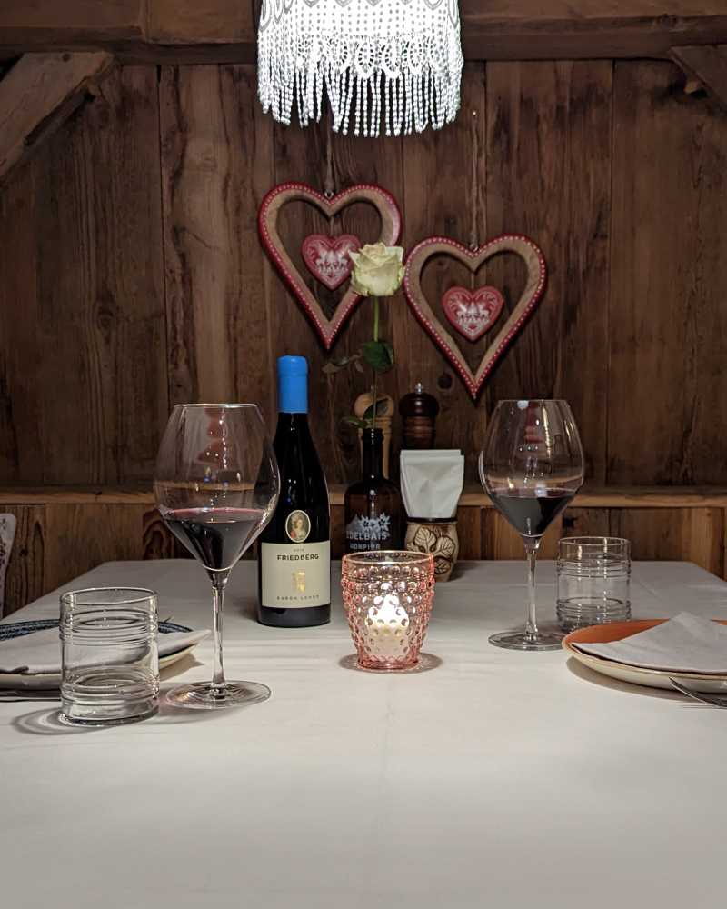Tisch in der Holzstube mit Wein und Tiroler Herzdekoration